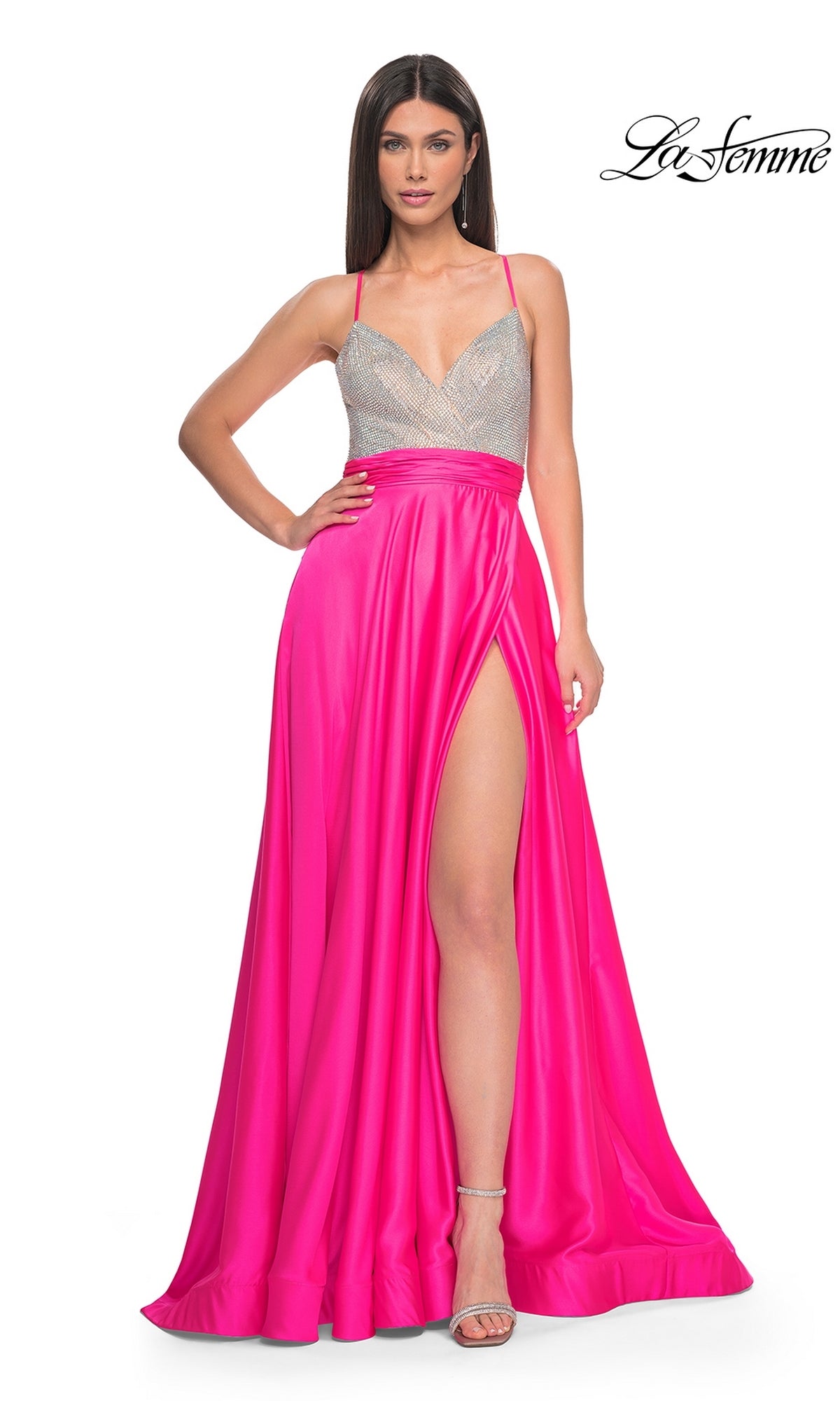 A woman poses confidently in the La Femme Neon Pink Long Prom Dress 31448, featuring thin straps, a beaded bodice, and a bright satin skirt with a high slit.